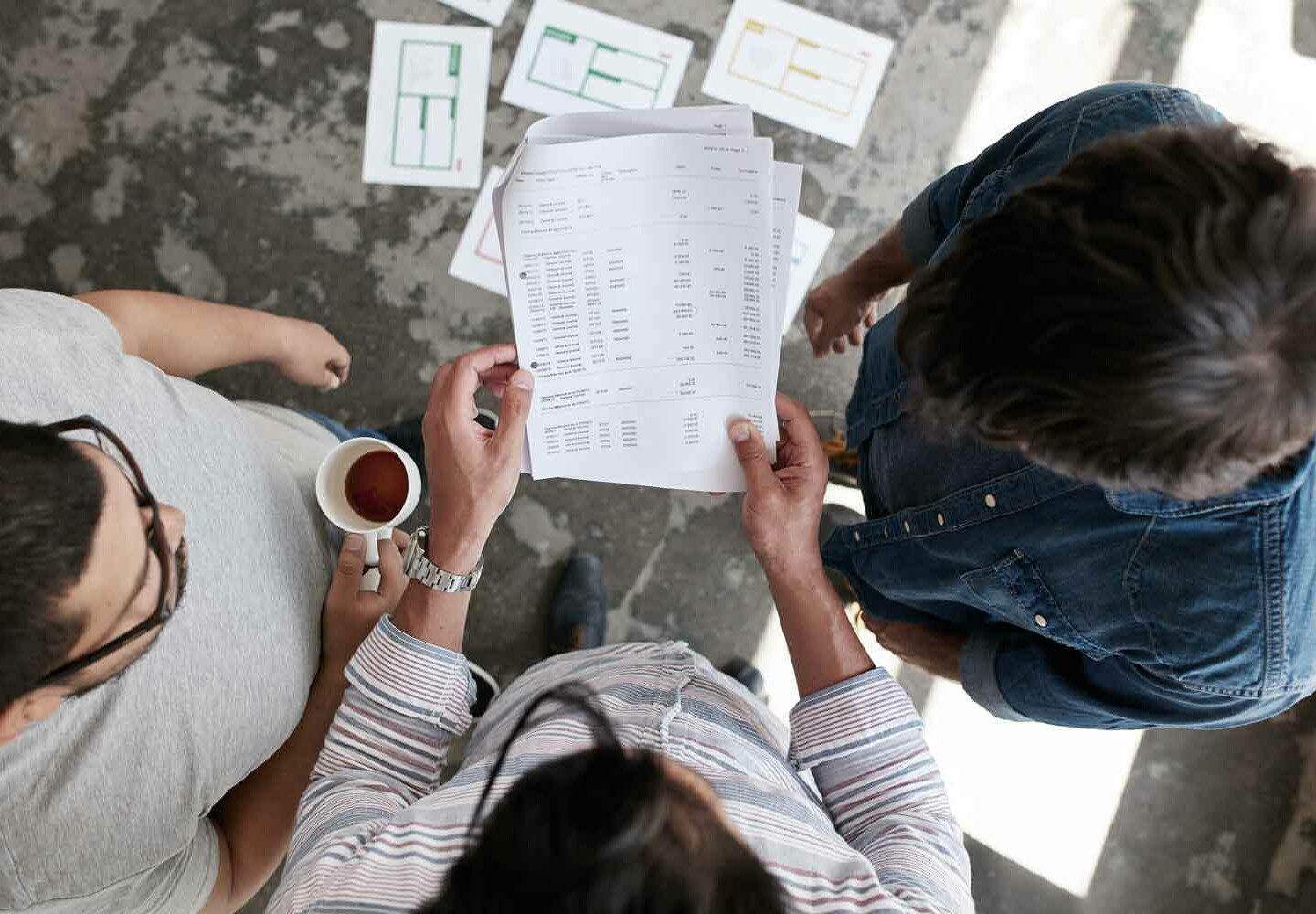 Três pessoas olhando para papéis que uma delas segura.