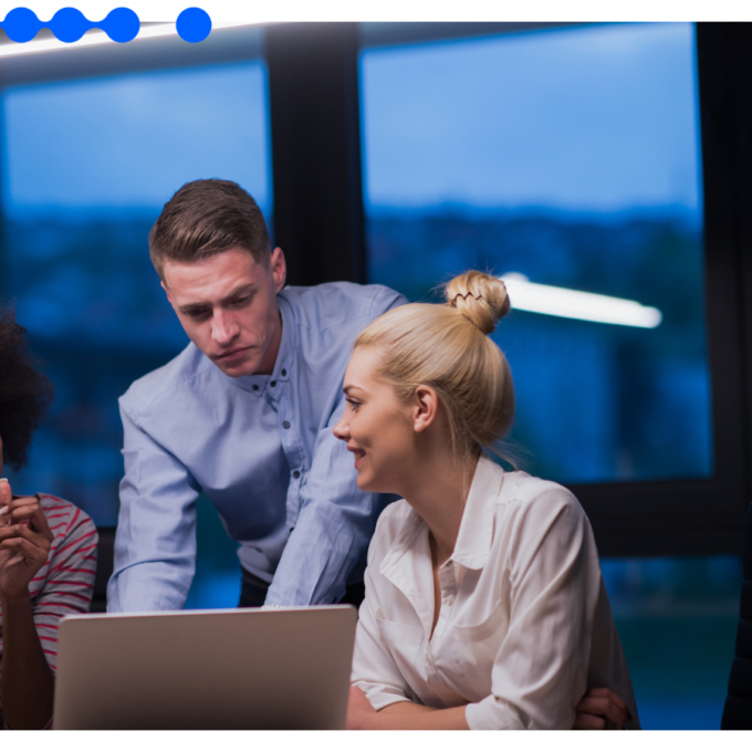 Three diverse professionals collaborating around a laptop in a modern office setting, analyzing workflows and discussing strategies for process mapping