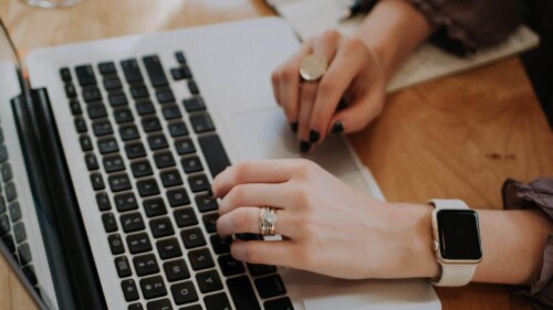 Pessoa com mãos femininas digitando sobre um notebook