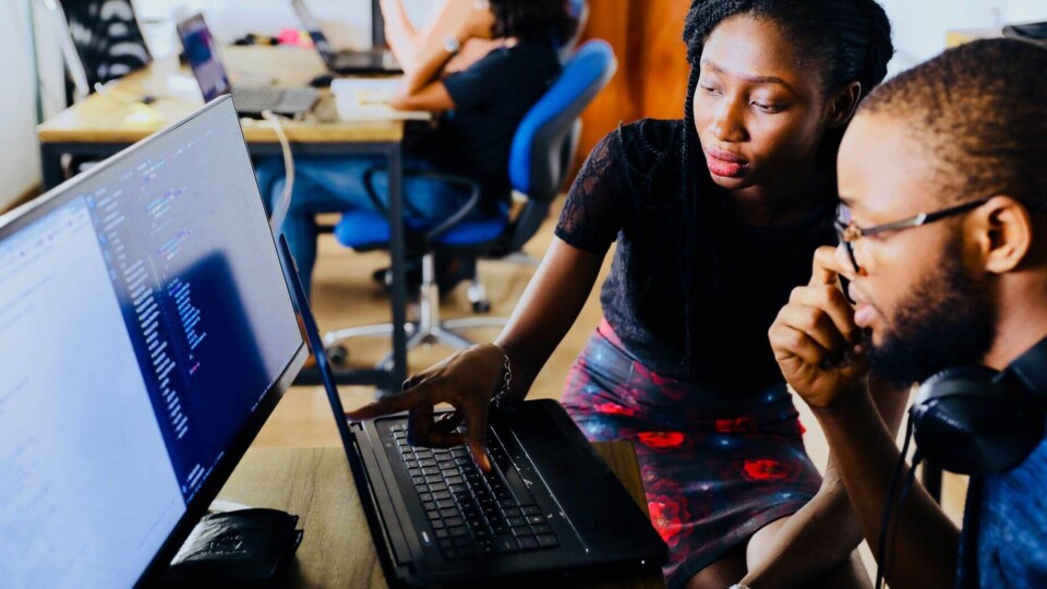 two people looking at a computer displaying lines of code