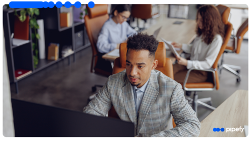 Profissional usando automação inteligente no computador em um escritório, com colegas ao fundo