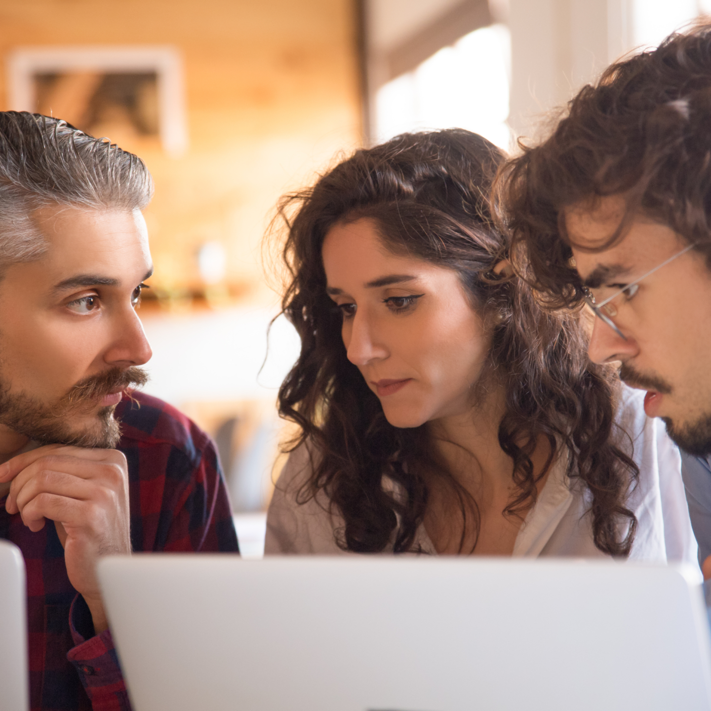 3 pessoas preocupadas olhando para um notebook