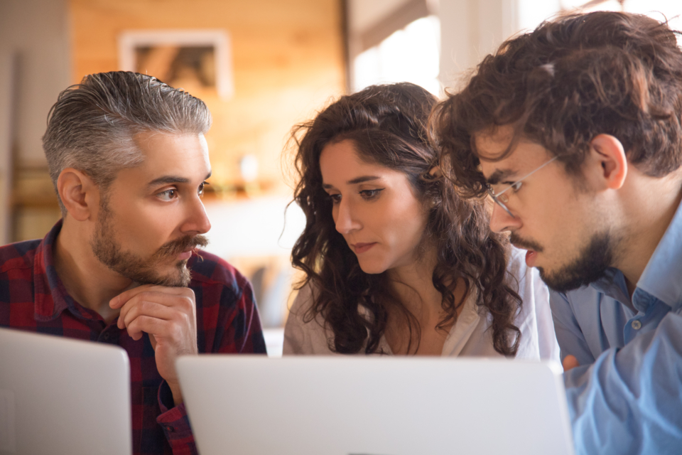 3 pessoas preocupadas olhando para um notebook