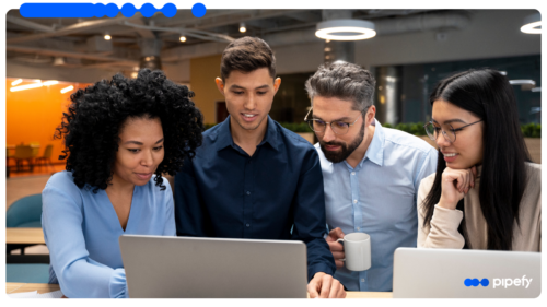 Quatro profissionais reunidos e olhando atentamente para a tela de um laptop em um escritório moderno, colaborando em projetos de automação de processos com IA