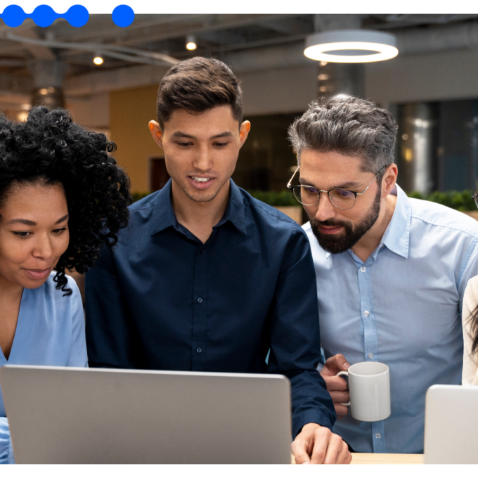 Quatro profissionais reunidos e olhando atentamente para a tela de um laptop em um escritório moderno, colaborando em projetos de automação de processos com IA