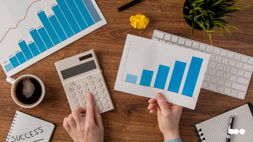 Relatórios financeiros com gráficos e calculadora em mesa, representando ineficiência na análise de crédito