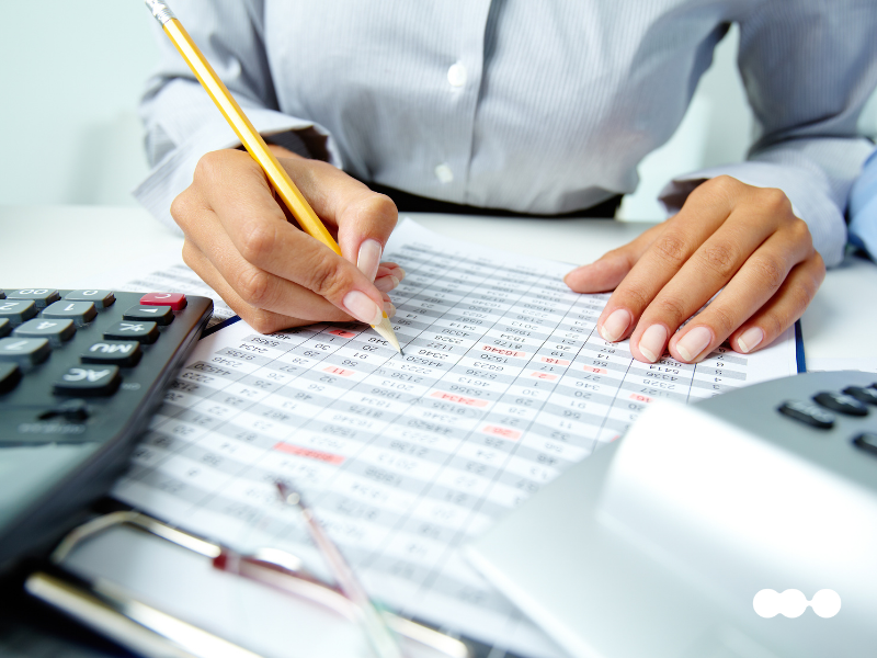 Professional analyzing financial spreadsheet next to calculators and documents