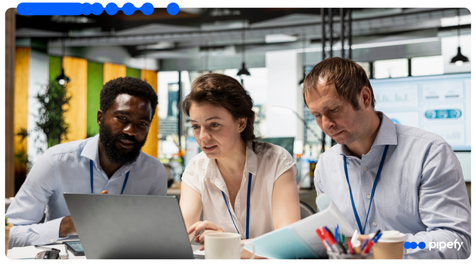 Equipe analisa dados em laptop e documentos em ambiente corporativo, representando a automação inteligente de processos com AI Workers em fluxos operacionais