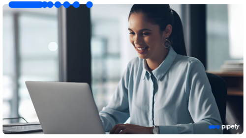 Smiling young woman working on a laptop in a bright, modern office, configuring system integrations through an iPaaS platform