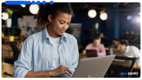 Mulher jovem trabalhando em um laptop em um ambiente de escritório colaborativo.