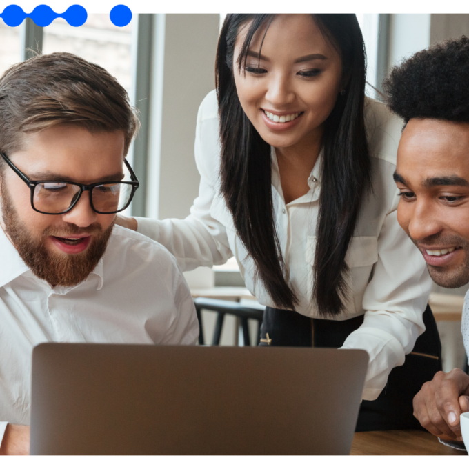 Três profissionais em um escritório moderno, sorrindo e colaborando ao redor de um laptop, simbolizando a busca por eficiência operacional com IA em seus processos internos