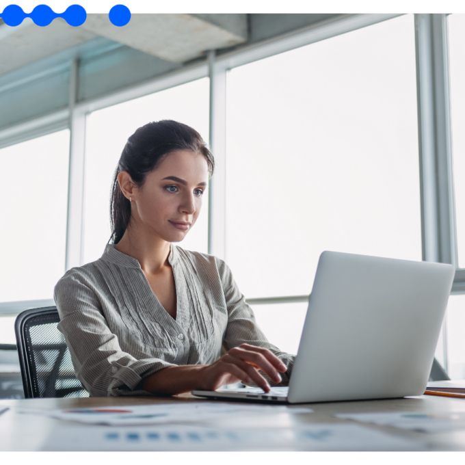 Jovem profissional focada trabalhando em um laptop em um escritório corporativo moderno e iluminado, analisando dados para otimizar um processo end-to-end de sua empresa