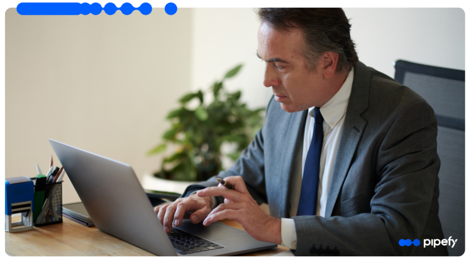 Senior finance professional in a suit working intently on a laptop to manage finance workflow automation at his desk