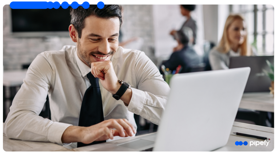 Smiling male professional using a laptop to manage AI workflows in a modern office environment