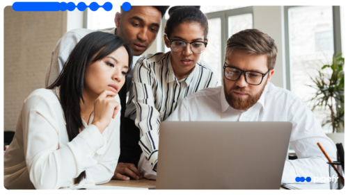 Diverse team of professionals collaborating on a laptop in a modern office, analyzing operations to understand what is a Shared Services Center