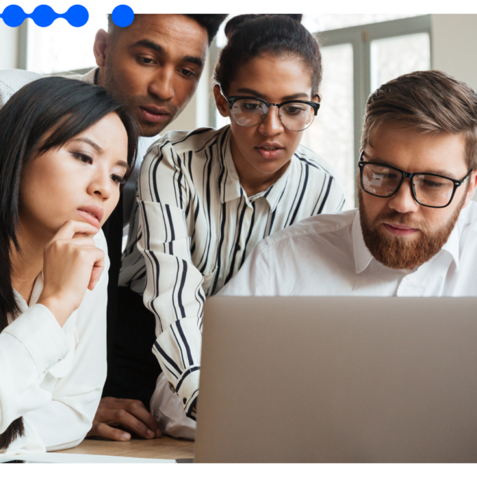 Diverse team of professionals collaborating on a laptop in a modern office, analyzing operations to understand what is a Shared Services Center