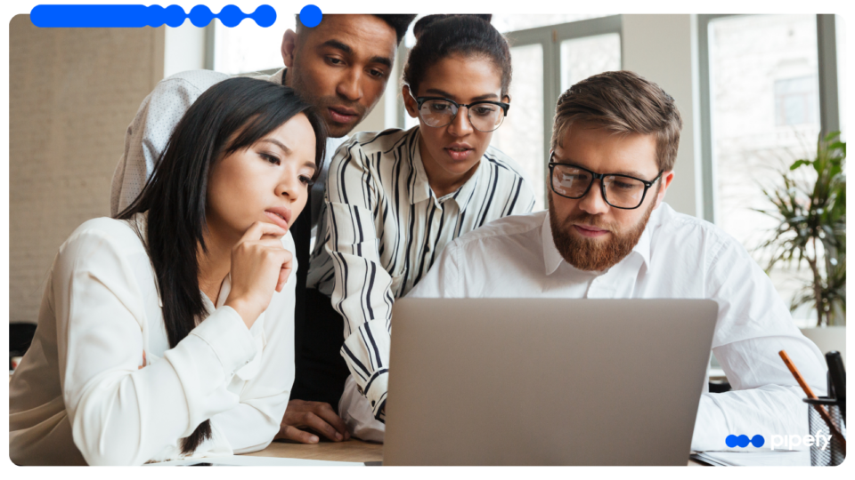Diverse team of professionals collaborating on a laptop in a modern office, analyzing operations to understand what is a Shared Services Center