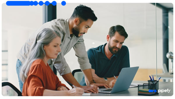 Equipe de risco e compliance analisa dados em um laptop durante reunião, tema da automação de background check no setor financeiro com Agentes de IA