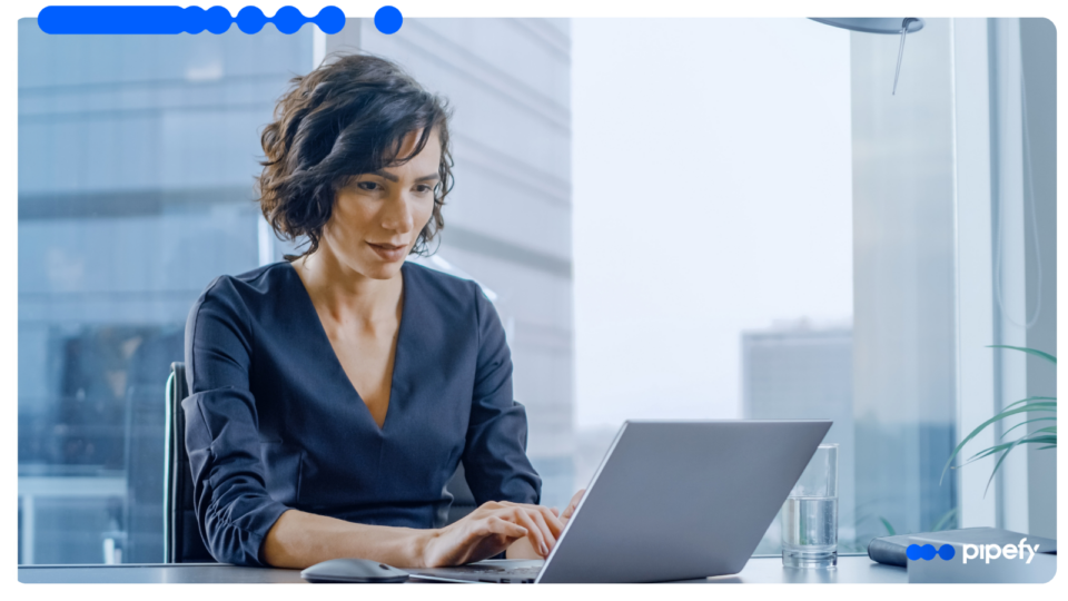 Executiva de cabelo curto trabalhando concentrada em um laptop num escritório moderno e bem iluminado, realizando a gestão de seguros