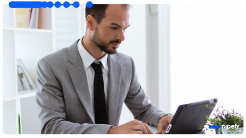 A business professional in a grey suit working on a tablet in a bright office, analyzing data to evaluate a risk score