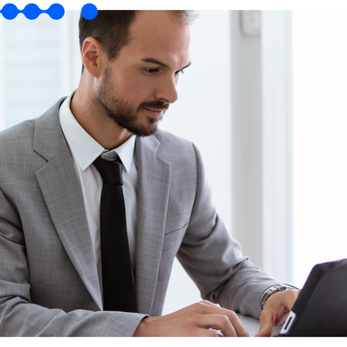A business professional in a grey suit working on a tablet in a bright office, analyzing data to evaluate a risk score