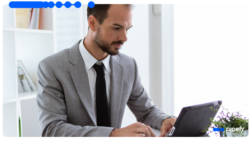 A business professional in a grey suit working on a tablet in a bright office, analyzing data to evaluate a risk score