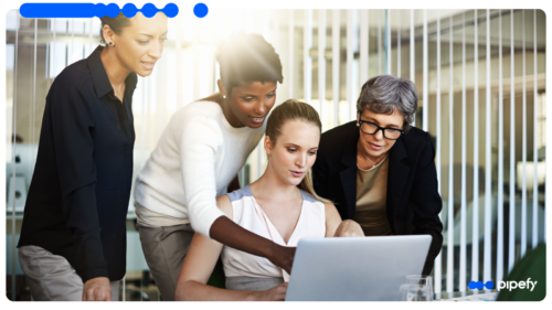 Equipe de vendas reunida em torno de um laptop analisa o pipeline, ilustrando como um CRM para B2B organiza o ciclo comercial