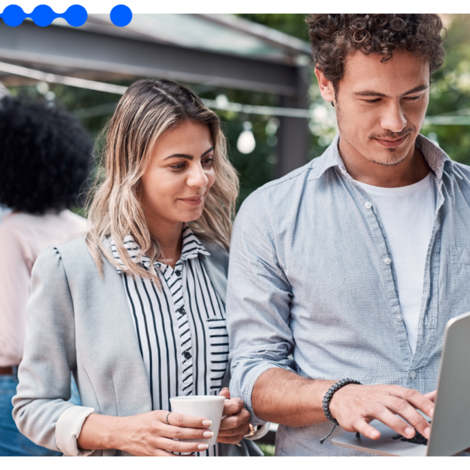 Equipe técnica revisa decisões em laptop enquanto outros profissionais colaboram ao fundo, ilustrando o ofício por trás de uma plataforma de IA empresarial