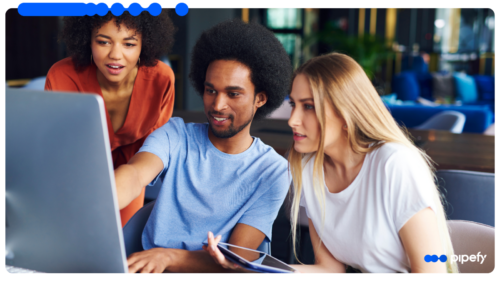 Três profissionais reunidos em ambiente corporativo moderno, analisando em um laptop os passos do framework de orquestração agêntica para sair do piloto