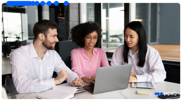 Three colleagues collaborate around a laptop in a modern office, orchestrating procurement workflow automation from intake to payment
