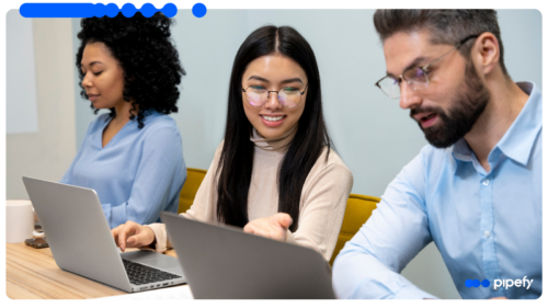 Three colleagues collaborate around laptops in a bright modern office, discussing procurement automation for an enterprise B2B operation