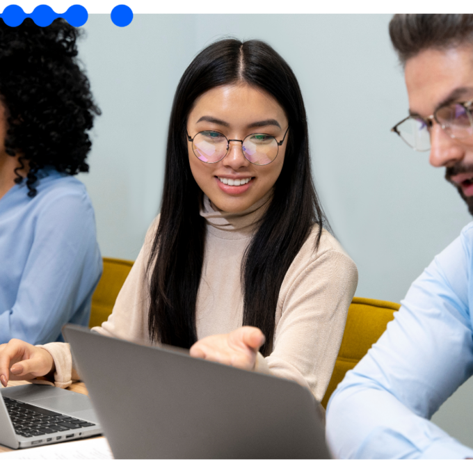 Three colleagues collaborate around laptops in a bright modern office, discussing procurement automation for an enterprise B2B operation