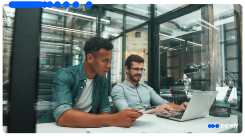 Two colleagues review work on a laptop in a modern office, reflecting how enterprise IT brings shadow AI under governance