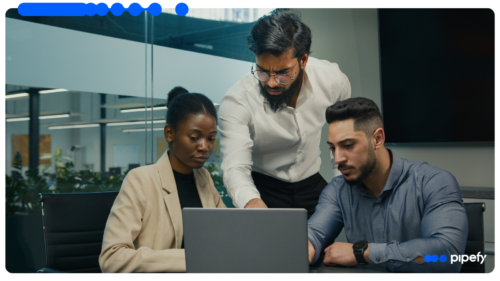 Three IT colleagues gather around a laptop in a modern office, evaluating an enterprise automation platform against governance criteria