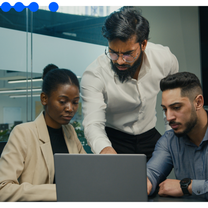 Three IT colleagues gather around a laptop in a modern office, evaluating an enterprise automation platform against governance criteria