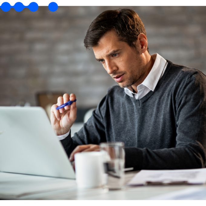 A focused IT leader studies his laptop at a desk, evaluating an enterprise systems integration that works on top of existing systems rather than replacing them