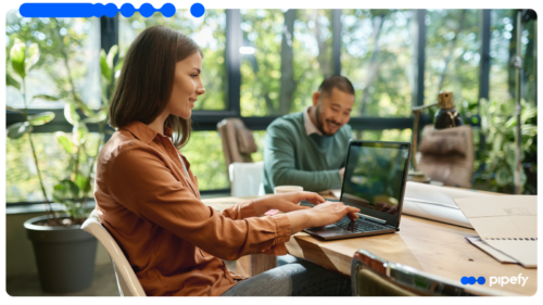 Two IT professionals work on laptops in a modern office, illustrating an IT modernization strategy that orchestrates systems on top of existing tools