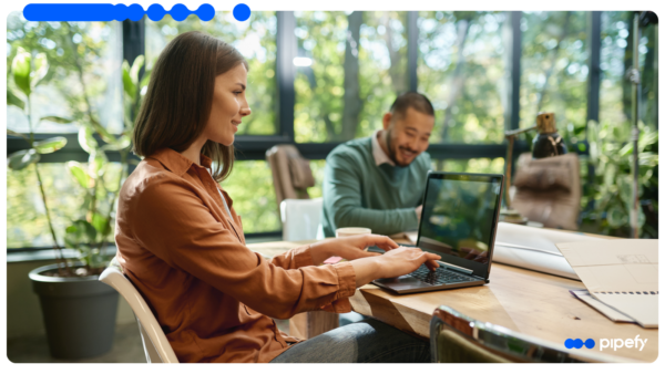 Two IT professionals work on laptops in a modern office, illustrating an IT modernization strategy that orchestrates systems on top of existing tools