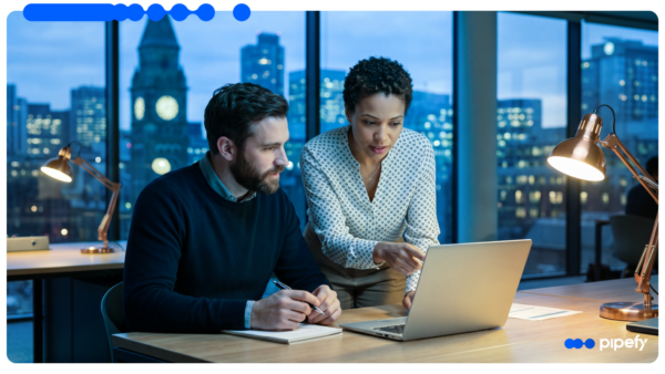 Two enterprise professionals reviewing Agentic AI for enterprise on a laptop in an office at night