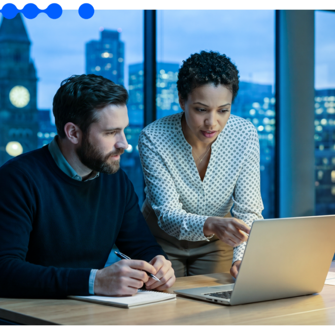 Two enterprise professionals reviewing Agentic AI for enterprise on a laptop in an office at night