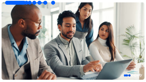 Four business professionals analyze AI ROI on a laptop during a meeting in a modern corporate office