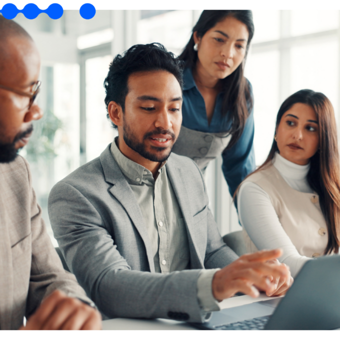 Four business professionals analyze AI ROI on a laptop during a meeting in a modern corporate office